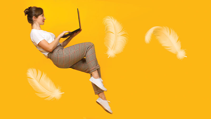 ragazza che fluttua tra le piume con in mano il pc